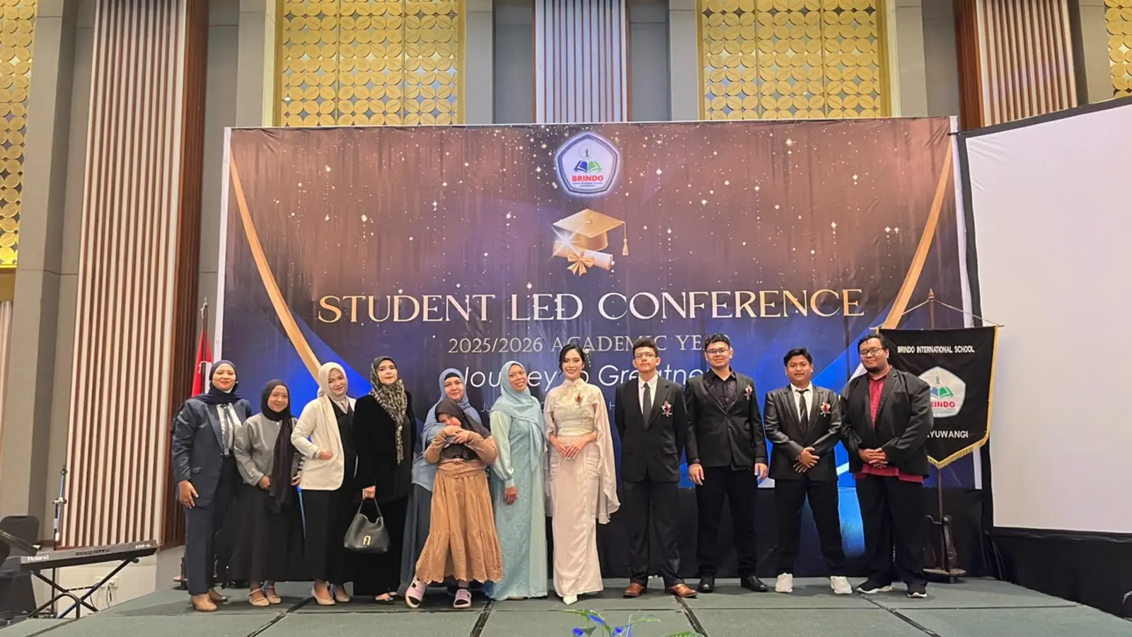Senior High School graduates pose with their parents and teachers on the Student Led Conference stage.