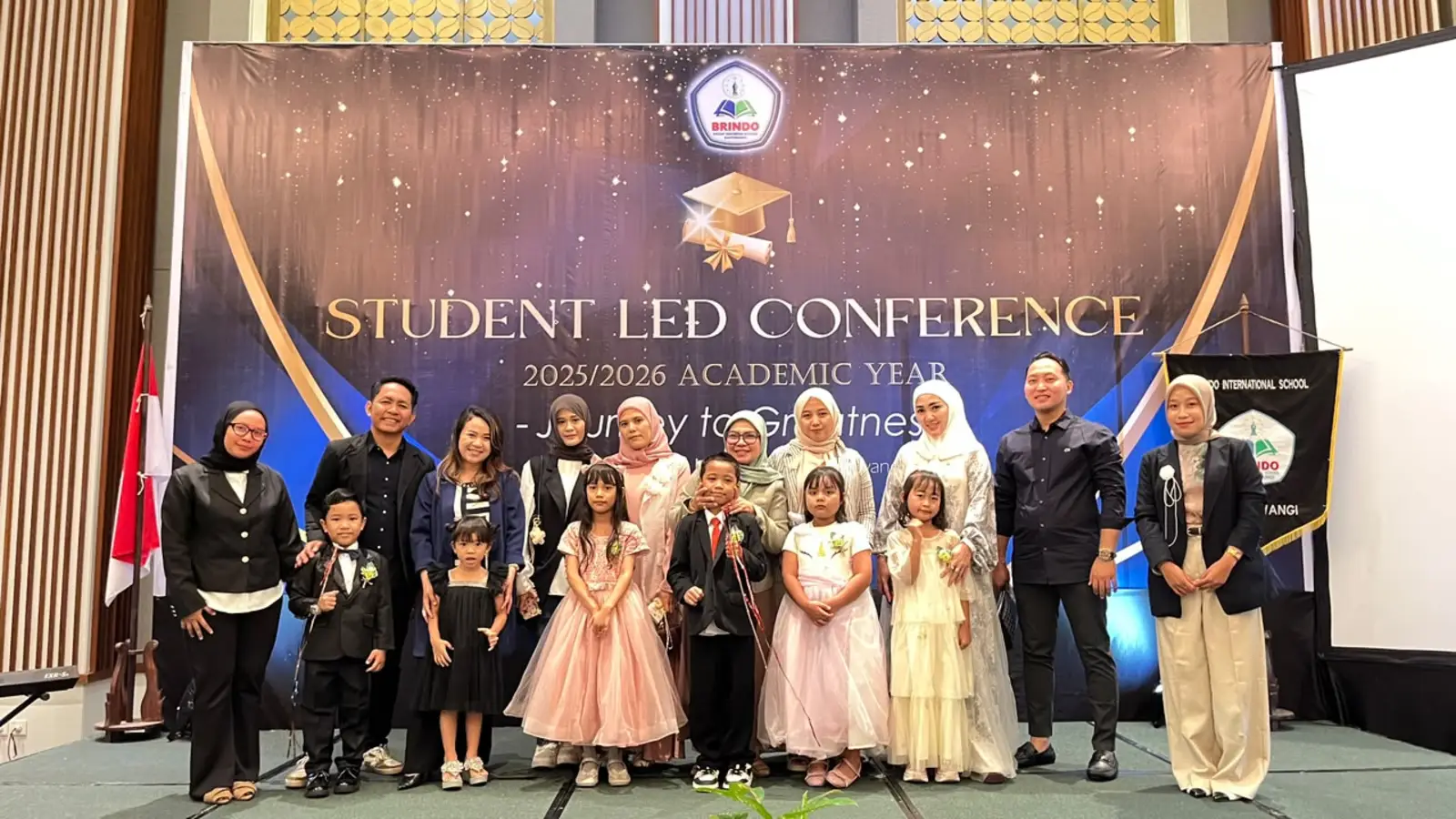 Kindergarten graduates with their teachers and parents, celebrating graduation dressed in their finest.
